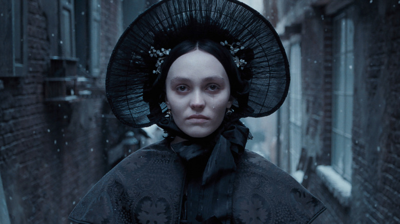 Ellen Lily-Rose Depp berpakaian hitam di jalan bersalju di Nosferatu