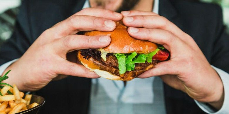 Orang yang memegang roti burger dengan sayuran dan kredit daging: Sander Dalhuisen