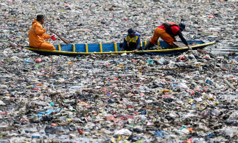 Petugas membersihkan tumpukan sampah plastik yang mengambang di Sungai Citisum di Bandung, Indonesia.