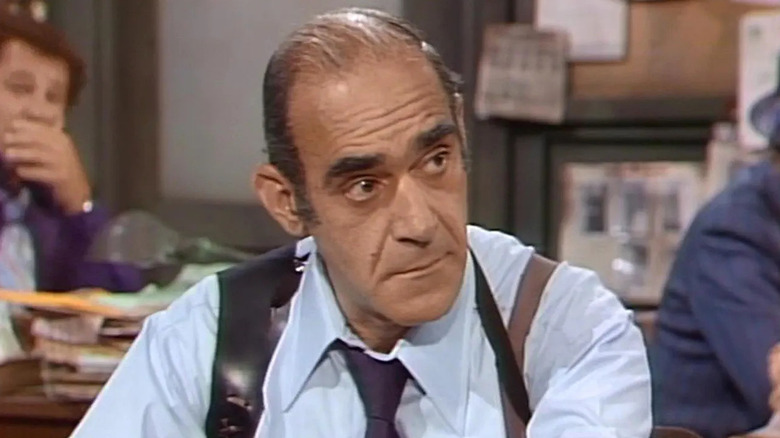 Abe Vigoda sebagai Sersan Philip K. Fish duduk di mejanya di Barney Miller