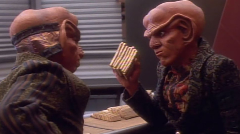 Quark memegang segenggam Latinum yang ditekan emas di Star Trek: Deep Space Nine