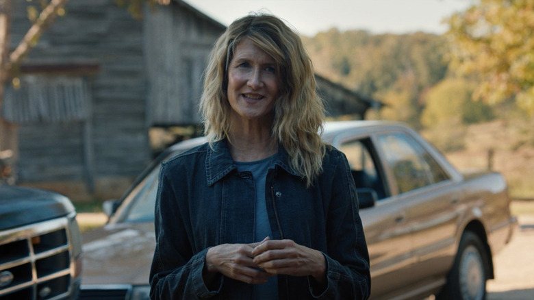 Laura Dern's Elizabeth Gilbert berdiri di depan beberapa mobil dan gudang di persidangan dengan api