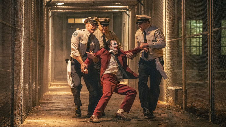 Brendan Gleeson Sebagai Petugas Koreksi Jackie Sullivan Menonton Fleck Arthur dari Joaquin Phoenix diseret melalui halaman penjara di Joker: Folie à Deux