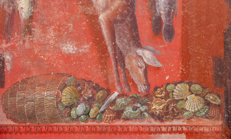 Close-up dinding frescoed; Ini memiliki latar belakang merah dan menunjukkan tumpah ruah dengan buah dan cangkang yang tumpah di latar depan. Bangkai babi menggantung dari atas.