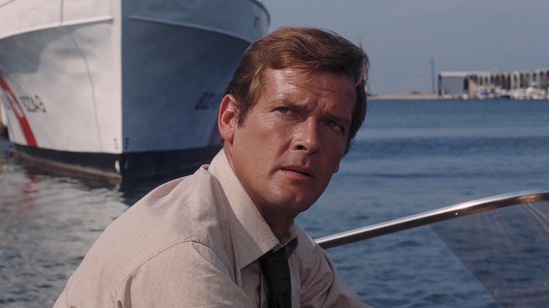 James Bond Roger Moore mendongak saat dia berdiri di perahu di Live and Let Die