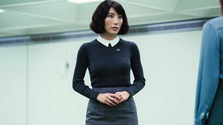 Dichen Lachman sebagai Ms. Casey berdiri di kantor Lumon di Severance