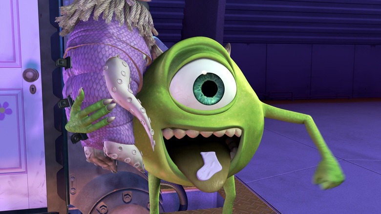 Mike Wazaowski menjulurkan lidahnya. Ada kaus kaki di mulutnya. Dia memiliki seorang gadis kecil yang digantung di bahunya. Dari Monsters, Inc.