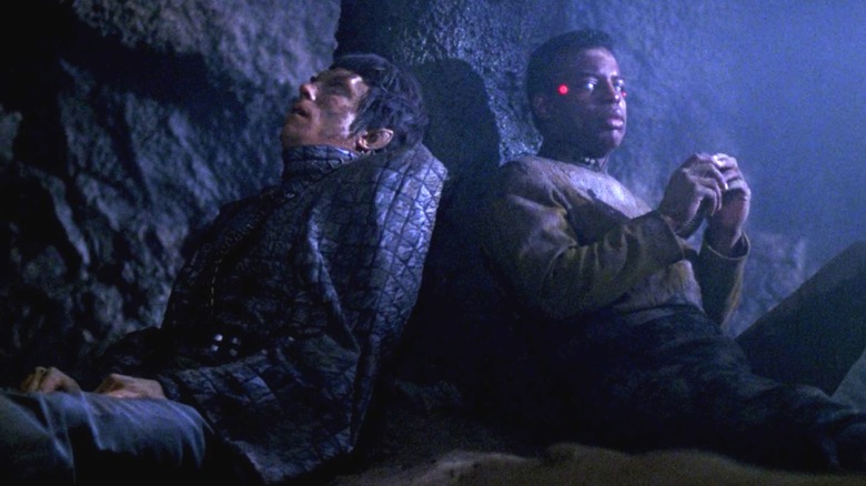 Seorang Romulan dan Geordi, duduk di atas tebing di planet yang gelap dan berbatu. Visor Geordi tidak aktif. Dari Star Trek: Generasi berikutnya.