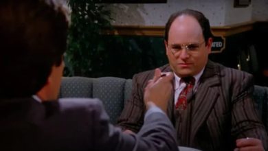 George, duduk di meja, menolak untuk makan makanan yang ditawarkan kepadanya. Adegan dari Seinfeld.