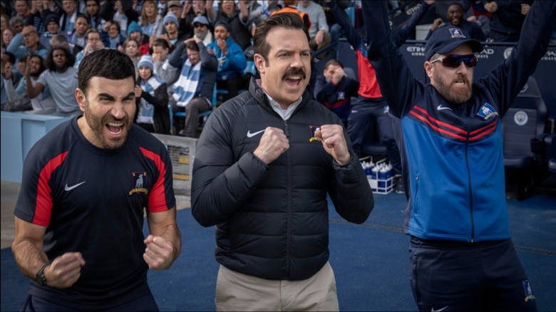 Roy Kent dari Brett Goldstein, Ted Lasso dari Jason Sudeikis, dan pelatih Brendan Hunt merayakan Ted Lasso