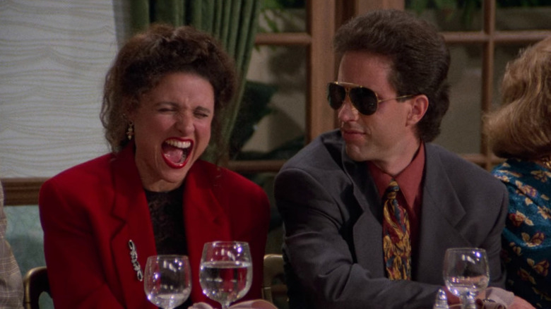 Julia Louis-Dreyfus 'Elaine Laughing dan Jerry Seinfeld's Jerry Mengenakan kacamata hitam di Seinfeld