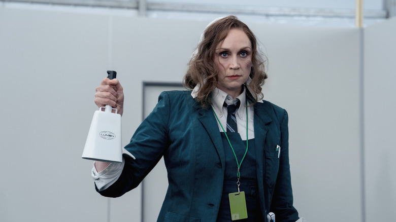 Gwendoline Christie sebagai karyawan Lumon Lorne memegang cowbell dan tampak berantakan di Severance Season 2