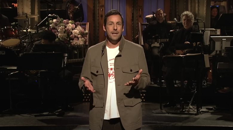 Adam Sandler berdiri di atas panggung, menjadi tuan rumah Saturday Night Live di 2019