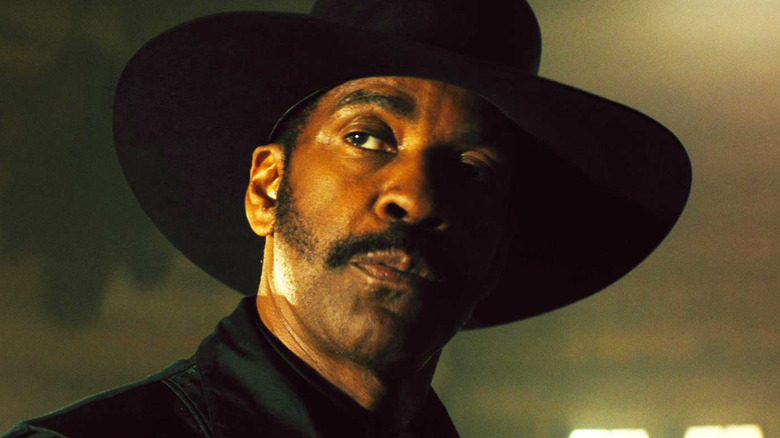 Sam Chisholm dari Denzel Washington mendongak sambil mengenakan topi di tujuh yang luar biasa