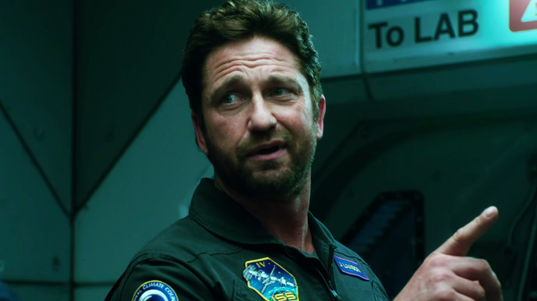Jake Lawson dari Gerard Butler menunjuk sesuatu di bagian dalam pesawat ruang angkasa di Geostorm