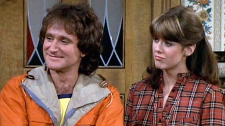 Robin Williams sebagai Mork dan Pam Dawber sebagai Mindy berdiri di ambang sebuah rumah di Mork & Mindy