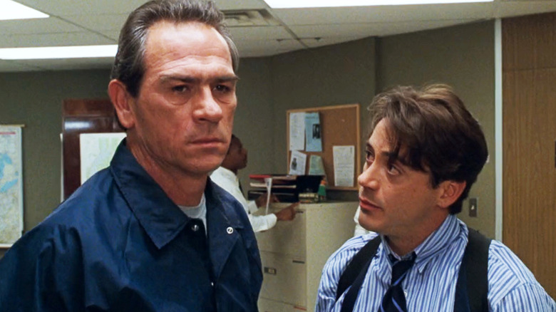 Robert Downey Jr sebagai Agen John Royce memandang Tommy Lee Jones sebagai Wakil Kepala Marsekal AS Samuel Gerard saat mereka berdiri di kantor di Marshals AS