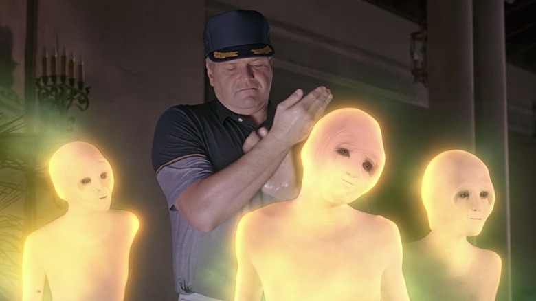 Walter, dengan topi, menggosok lengannya dan dikelilingi oleh tiga alien telanjang yang bersinar dari kepompong