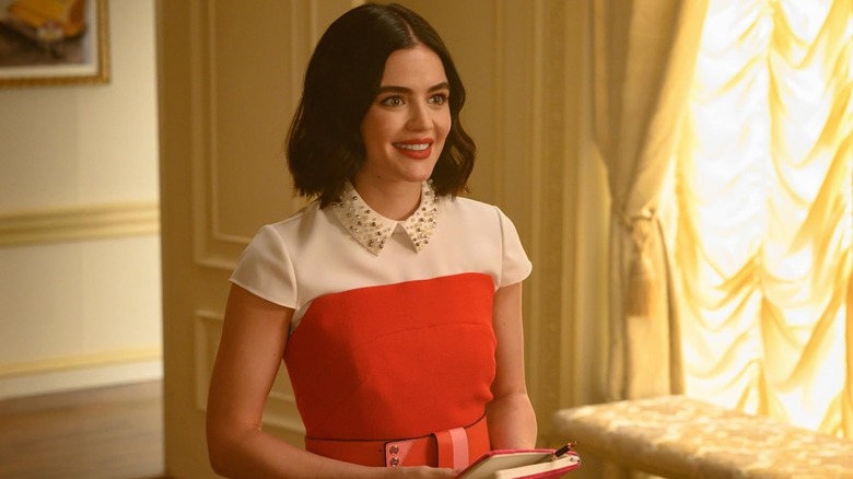 Lucy Hale sebagai Katy tersenyum sambil memegang buku catatan di Katy Keene
