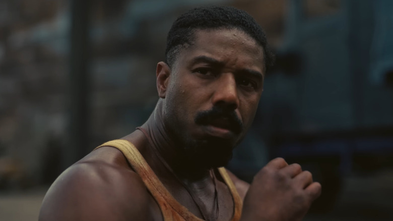 Michael B. Jordan sebagai asap duduk di luar klub di Sinners