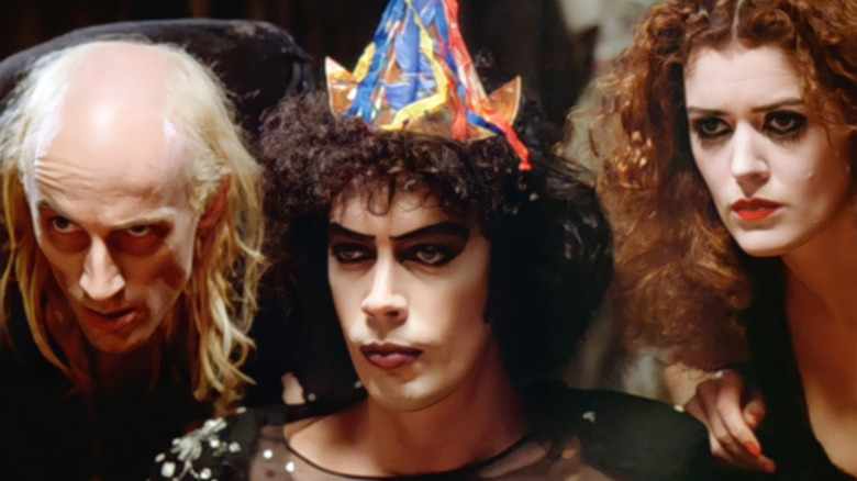 Riff Raff, Dr. Frank-N-Furter, dan Magenta melotot di atas meja dalam acara gambar horor berbatu