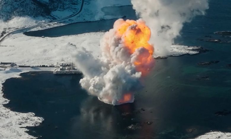 pemandangan udara awan jamur berwarna oranye yang naik dari laut yang dikelilingi oleh pegunungan es