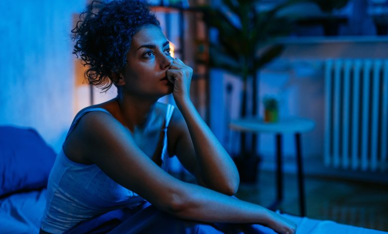 Seorang wanita dengan insomnia duduk di tempat tidur