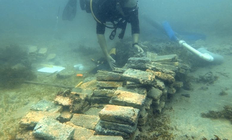 Penyelam memeriksa batu bata kuning di bawah air