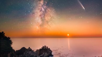 Foto pantai berbatu yang murni dengan Bima Sakti, bintang jatuh, dan planet pengaturan yang terlihat di langit
