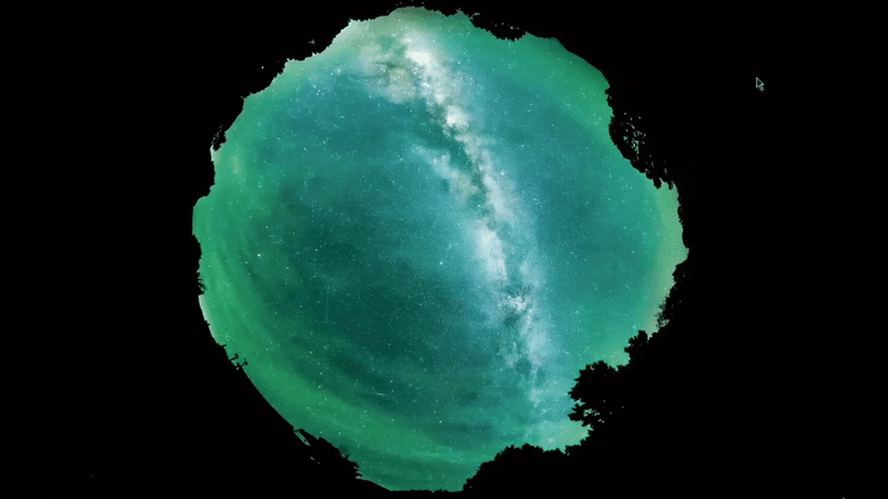 Riak bergerak melalui cahaya kabur hijau di langit malam dengan Milky Way yang cerah di belakang.