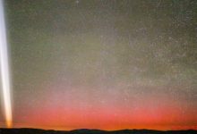 Gerakan cahaya putih di langit malam dengan aurora merah tepat di atas cakrawala