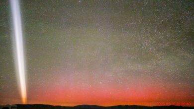 Gerakan cahaya putih di langit malam dengan aurora merah tepat di atas cakrawala