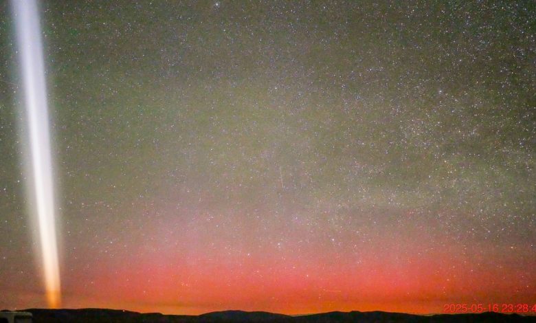 Gerakan cahaya putih di langit malam dengan aurora merah tepat di atas cakrawala