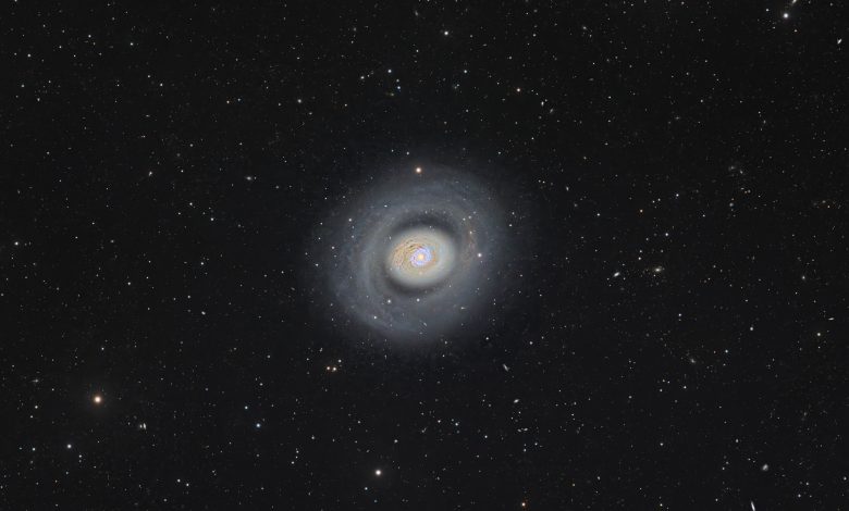 Galaksi spiral bundar dengan titik tengah yang cerah, terlihat di ratusan bintang latar belakang