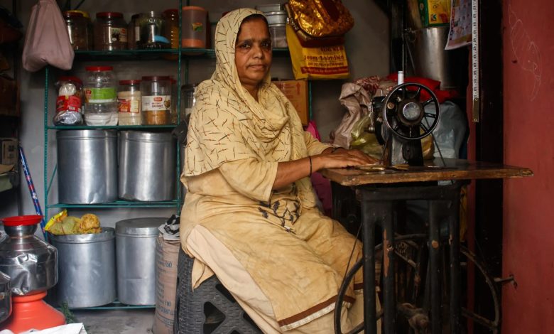 Foto seorang wanita India yang bekerja di mesin jahit