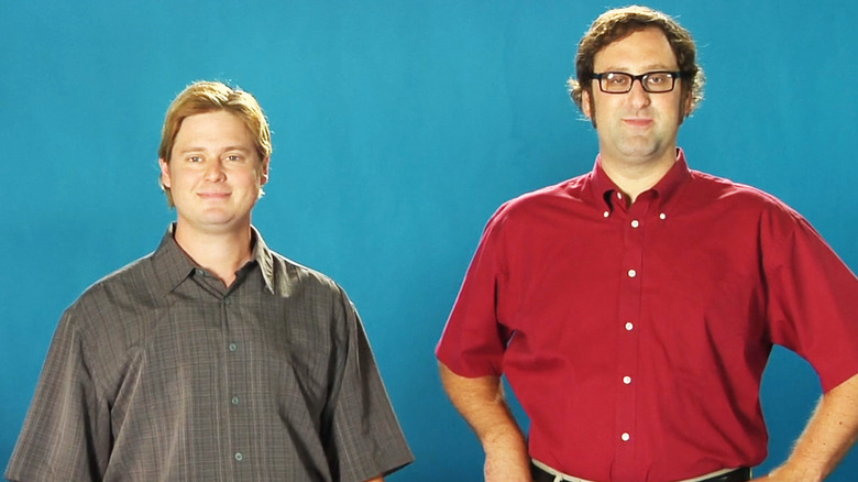 Tim Heidecker dan Eric Wareheim berdiri berdampingan dengan latar belakang biru di acara Tim dan Eric yang luar biasa, pekerjaan yang bagus