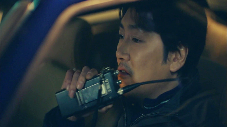 Lee Jae-Han (Cho Jin-Woong) berbicara tentang walkie-talkie di mobilnya di Signal (2016)