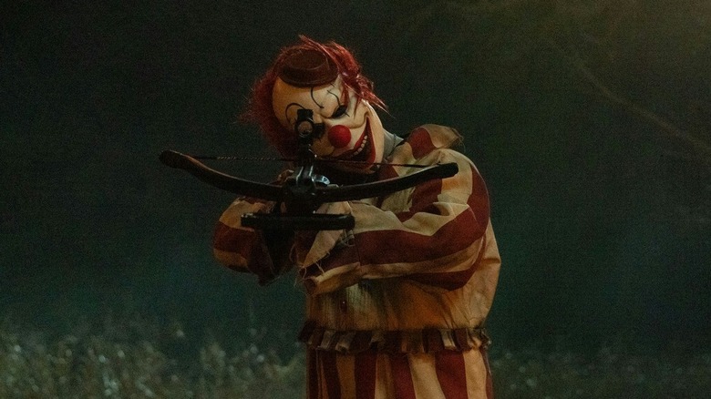 Frendo the Clown memegang panah otomatis di badut di ladang jagung