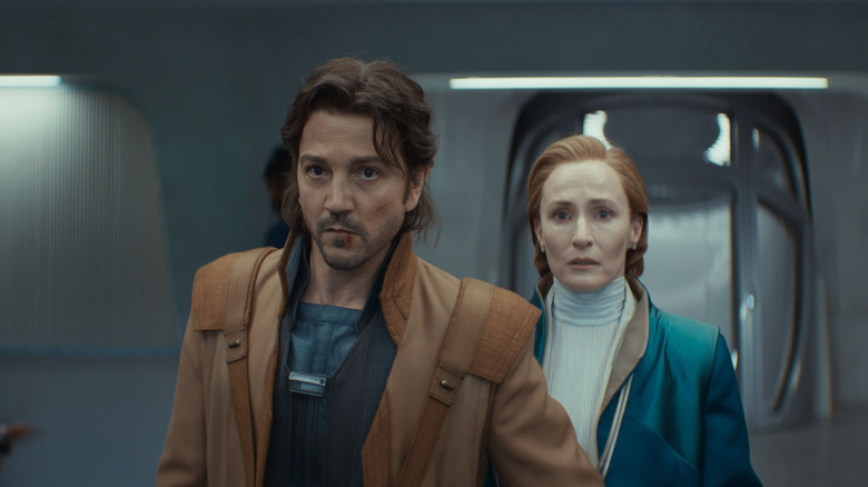 Diego Luna sebagai Cassian Andor berdiri di depan Genevieve O'Reilly sebagai Mon Mothma di Andor
