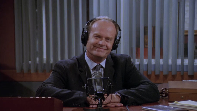 Crane Frasier Kelsey Grammer tersenyum saat dia duduk di meja studio radionya di Frasier