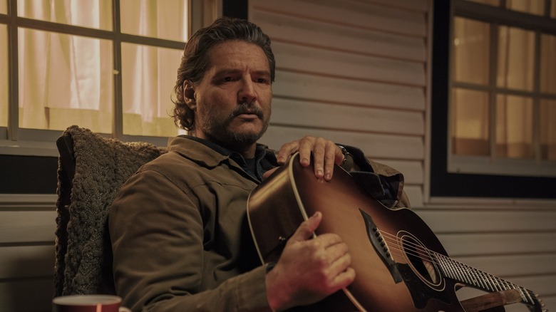 Joel memegang gitarnya di teras di The Last of Us