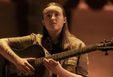 Bella Ramsey sebagai Ellie duduk dengan gitar di atas panggung di The Last of Us