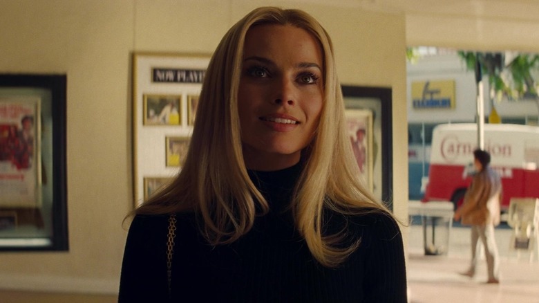 Margot Robbie sebagai Sharon Tate tersenyum di luar bioskop di Once Upon a Time di Hollywood