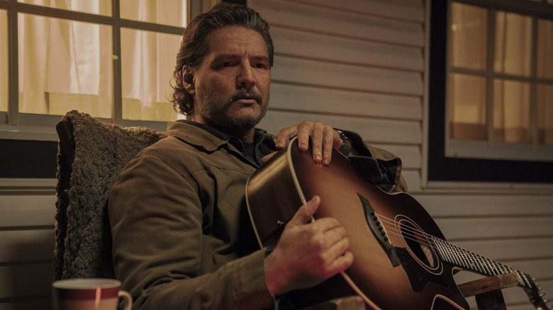 Joel memegang gitarnya di teras di The Last of Us