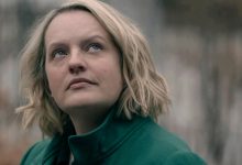 Juni (Elisabeth Moss) terlihat kontemplatif ke arah langit, mengenakan mantel hijau zamrud dalam kisah pelayan