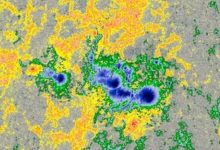 Gambar multicolor dari titik matahari di bawah sinar matahari yang dikelilingi oleh medan magnet yang tidak terlihat