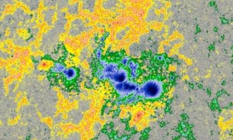 Gambar multicolor dari titik matahari di bawah sinar matahari yang dikelilingi oleh medan magnet yang tidak terlihat