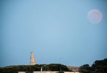 Foto bulan stroberi yang terbit di atas torre del serpe di Otranto, Italia.