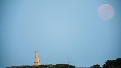 Foto bulan stroberi yang terbit di atas torre del serpe di Otranto, Italia.
