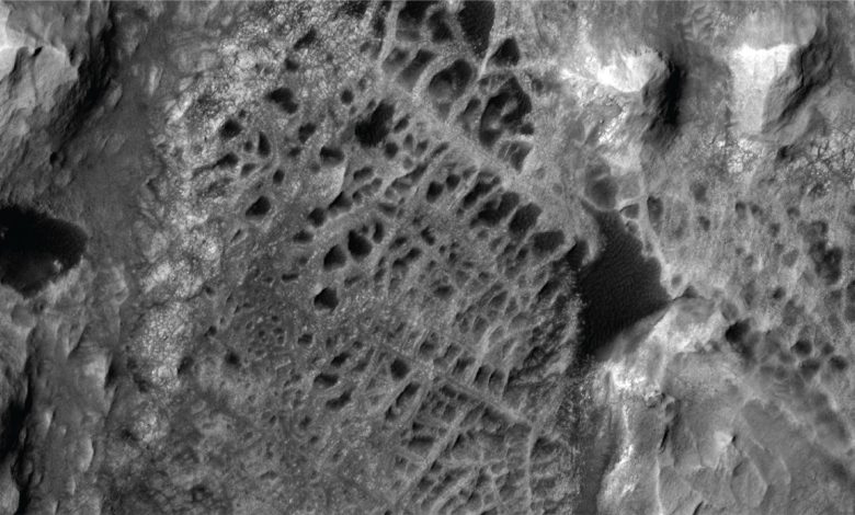 Gambar satelit hitam dan putih dari fitur permukaan seperti spiderweb di Mars